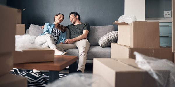 couple sitting on a couch with moving boxes nearby